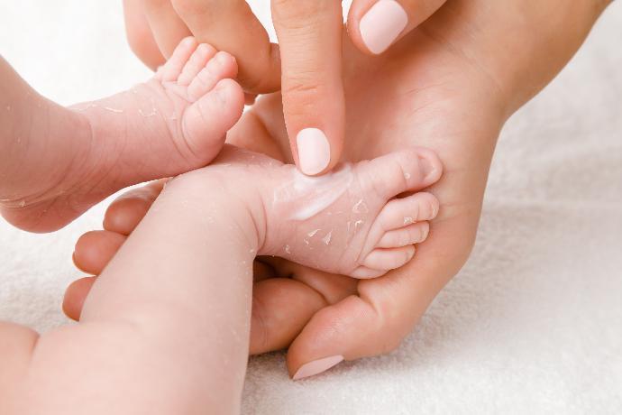 close up of person rubbing cream on a babies feet