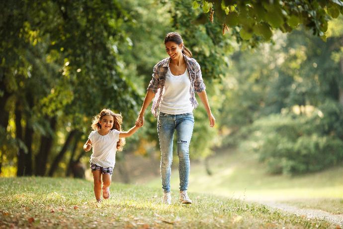 Mother and daughter running hand in hand trough a forrest